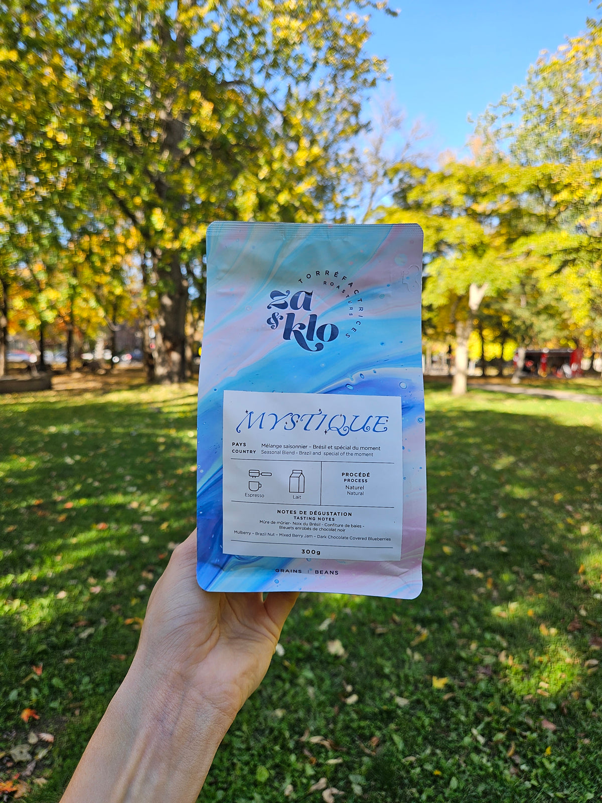 Mystique, un mélange du Brésil Honey et d’un café éthiopien produit par Heleanna Georgalis. Le sac met en avant des notes de dégustation de tangerine, caramel salé et chocolat, avec une typographie visible affichant le nom « Mystique ». Ce café se déguste en espresso, latte ou en French press et reflète la personnalité de Za : un mystère à découvrir, délicat et subtil. Idéal pour les moments de dégustation contemplative, comme les soirs de pleine lune.