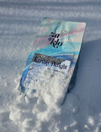 Image of Za & Klo coffee bag with reflective label, buried in snow. winter release of coffee. Coffee has notes of rose, pistachio, honey and orange blossom. Za and Klo's coffee named earthly delight.