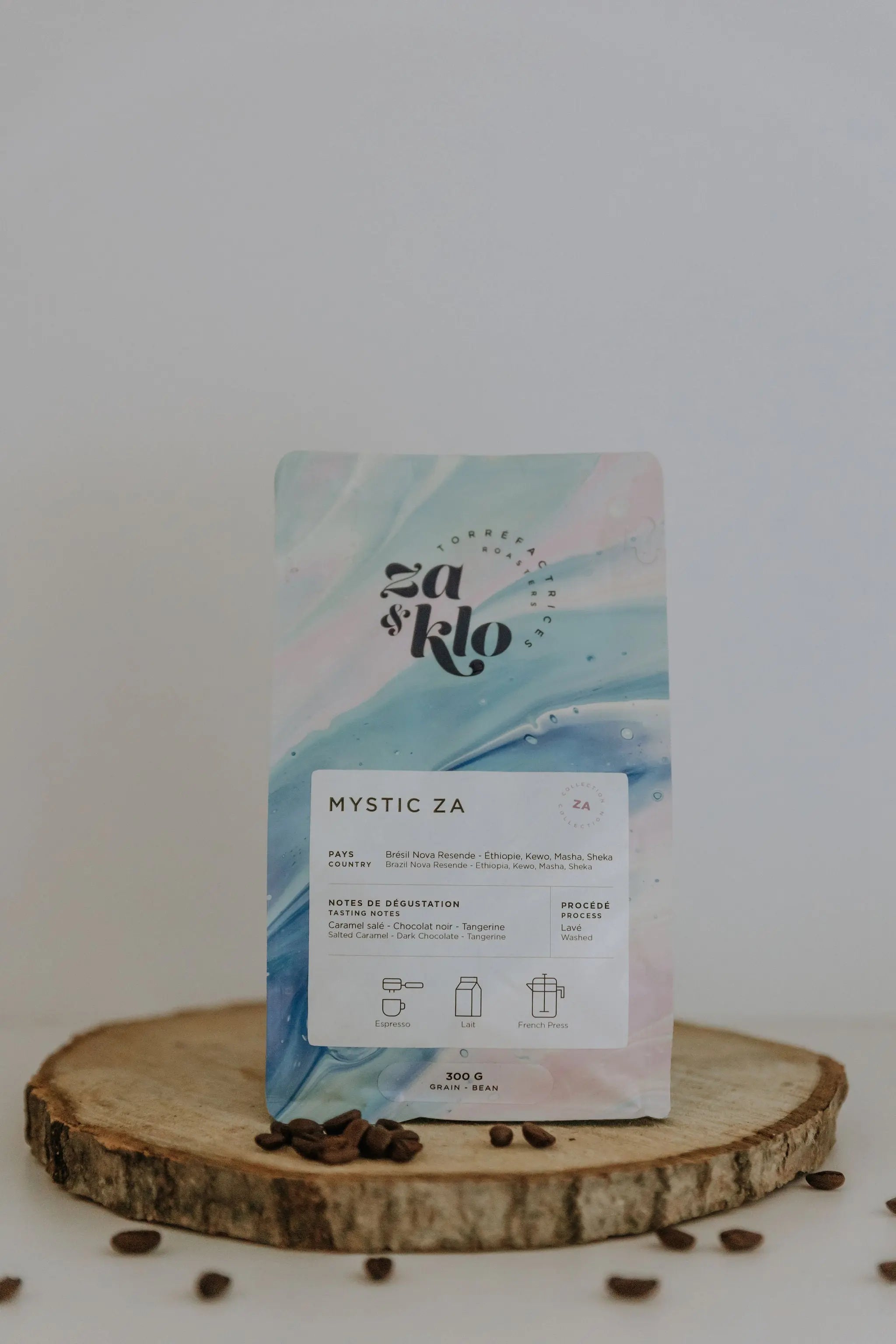 essin d’un sac de café illustrant Mystique, un mélange du Brésil Honey et d’un café éthiopien produit par Heleanna Georgalis. Le sac met en avant des notes de dégustation de tangerine, caramel salé et chocolat, avec une typographie visible affichant le nom « Mystique ». Ce café se déguste en espresso, latte ou en French press et reflète la personnalité de Za : un mystère à découvrir, délicat et subtil. Idéal pour les moments de dégustation contemplative, comme les soirs de pleine lune.