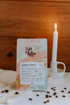 Photo café illustrant une torréfaction plus foncée du café du Guatemala produit par Juan Jose Torres. Le sac met en avant des notes de cacao, guimauve grillée et noix de macadam, avec une typographie visible affichant le nom « Torres Foncé » sur le sac. Cette version, plus foncée, reste délicate et mielleuse, idéale pour les boissons à base de lait comme le latte ou le cortado. Roasted by za and klo.