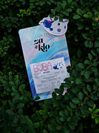 Image of Za and Klo Roasters bag of coffee titled Buba, from Moyinga, Burundi. The bag is nestled in green plants and features ladybug illustration. 