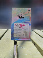 Photo de Minerva, un cafe Geisha « white honey » de Colombie produit par Sebastian Ramirez, avec un porte-clés en cristal attaché au sac. Le sac met en avant des notes fruitées, florales et herbacées, avec une typographie visible affichant le nom « Minerva ». Ce café complexe et surprenant révèle des saveurs de pêche et de basilic, idéal pour accompagner une burrata ou une pâtisserie aux fruits. Parfait en cold brew ou pour over. Torrefactrices Za et Klo.